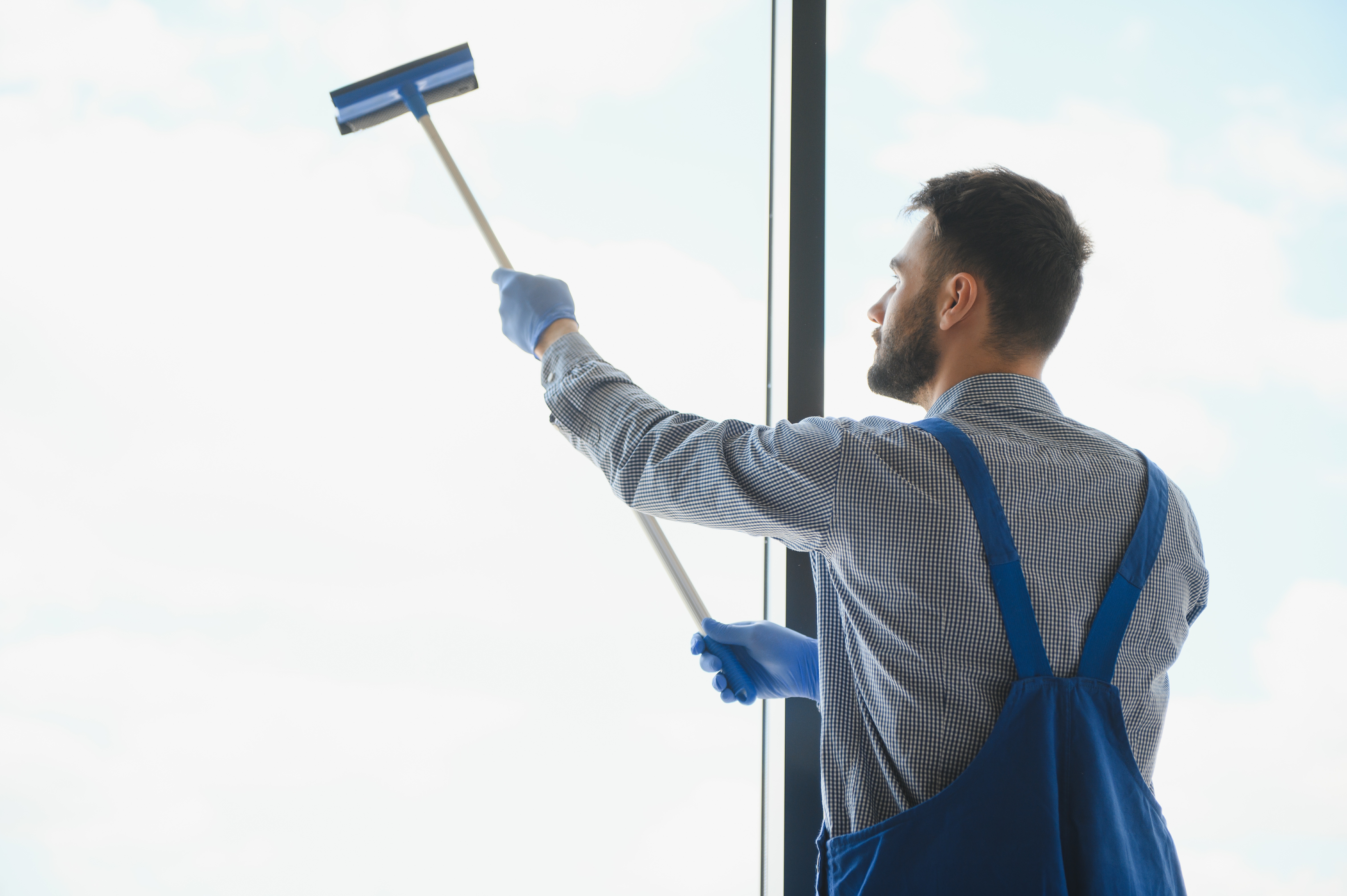 Professional window cleaner servicing a storefront with specialized equipment