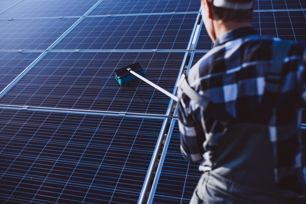 close up man cleaning solar panels with broom