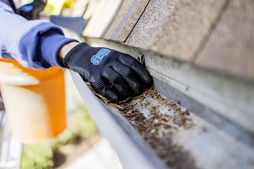 Technician cleaning gutters at a home in the Chicago suburbs