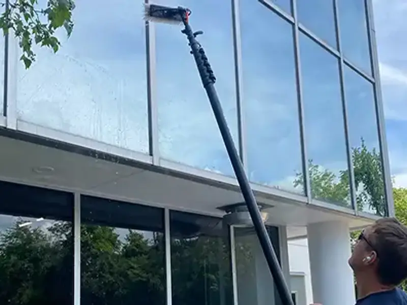 My Window Washing technician using a water-fed pole on a commercial building