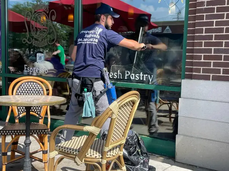Technician cleaning restaurant storefront windows